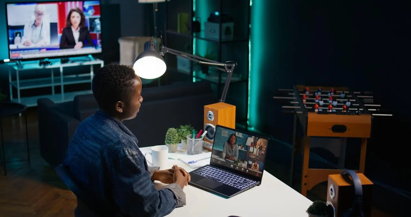 Fröhlicher Mitarbeiter winkt Kollegen in einer Telekonferenz zur Begrüßung.