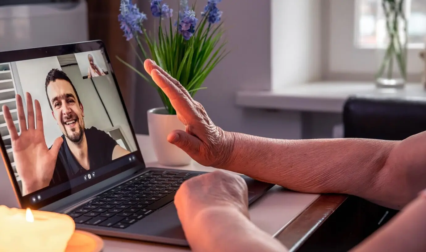 Eine alte Frau kommuniziert mit ihrem Sohn per Videoverbindung über einen Laptop.